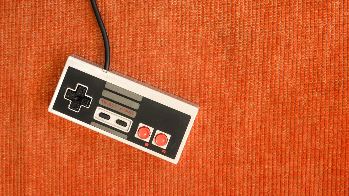 Retro game controller resting on an orange sofa