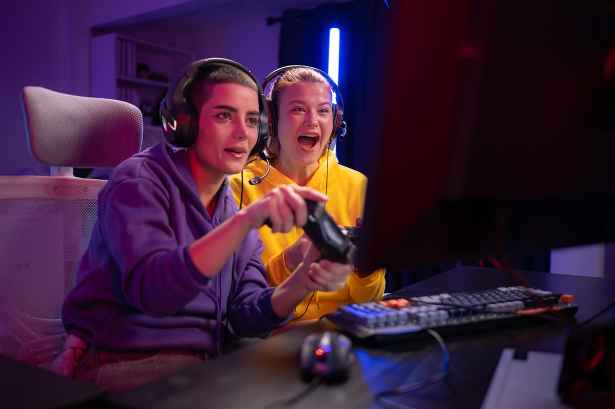 Two friends playing a video game together with wireless controllers in a colorful gaming room