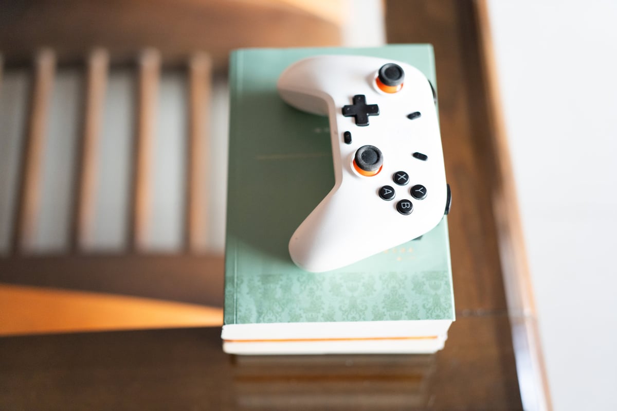 White wireless controller resting on a book on a wooden table in a modern home interior